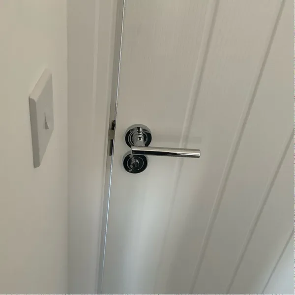 Photo of the bedroom door, with its lever handle, closed against the frame
